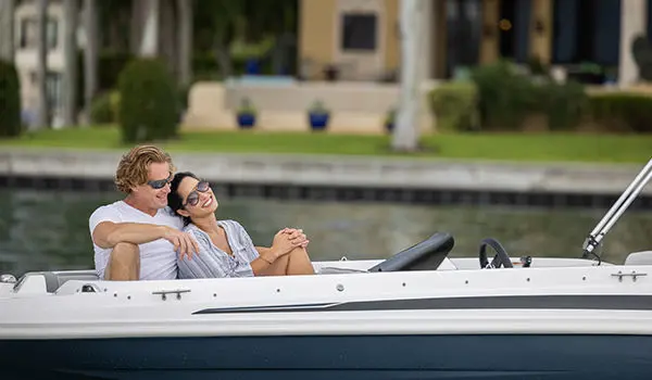 A couple cuddling on the bow seats of a Hurricane SunDeck Sport 205 OB deck boat.
