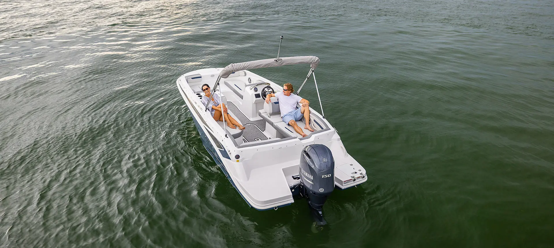 Rear view of a couple lounging on the stern seats on a Hurricane SunDeck Sport 205 OB deck boat.