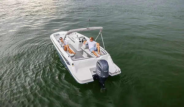 Rear view of a couple lounging on the stern seats on a Hurricane SunDeck Sport 205 OB deck boat.