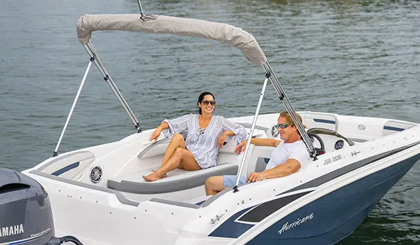 A couple smiling at each other while enjoying the stern lounge seating on a Hurricane SunDeck Sport 205 OB deck boat.