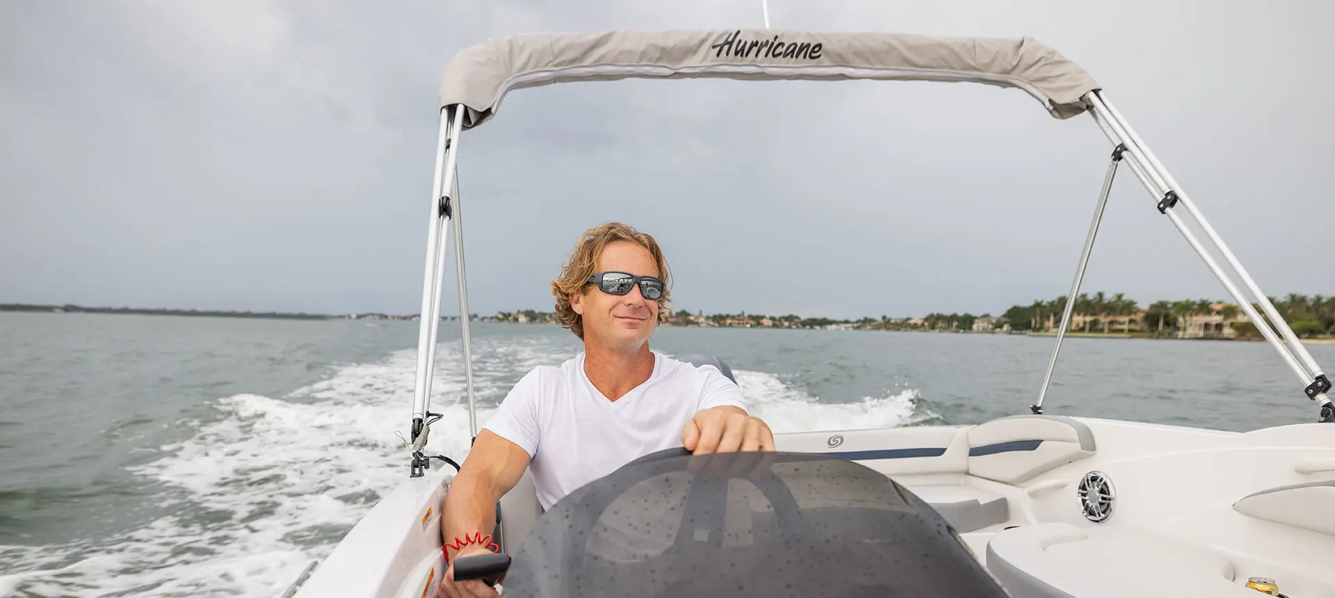 Man sitting at the helm of a Hurricane SunDeck Sport 205 OB deck boat.