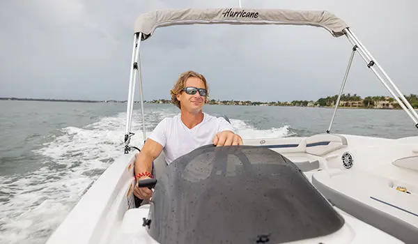 Man sitting at the helm of a Hurricane SunDeck Sport 205 OB deck boat.