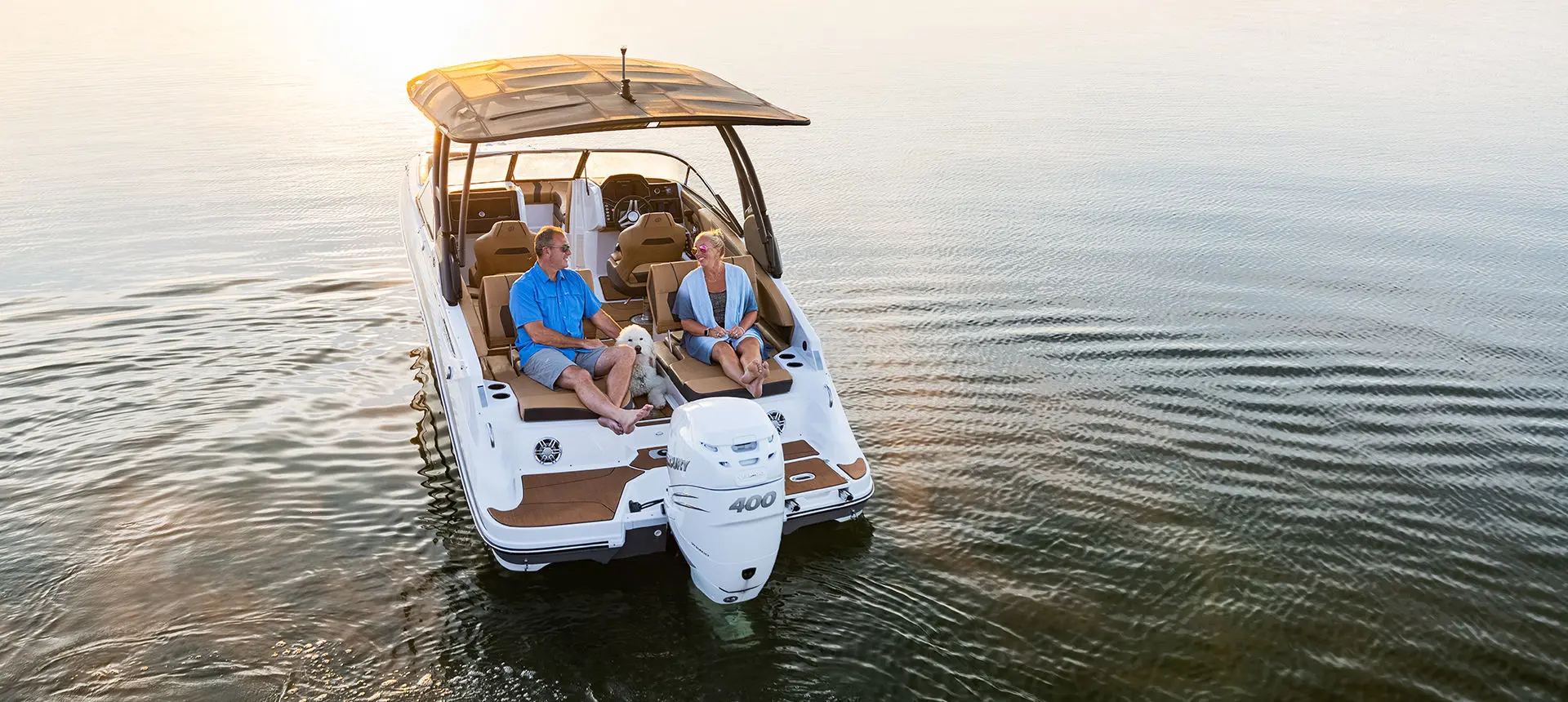 a couple and their dog relaxing on the bow lounge seats on a hurricane entertainment boat