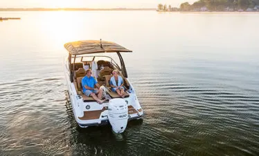a couple and their dog relaxing on the bow lounge seats on a hurricane entertainment boat