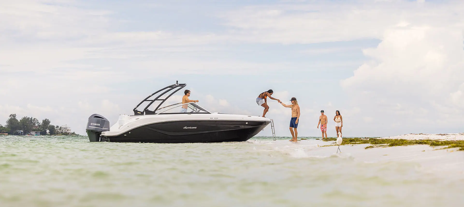 woman stepping off the bow of a hurricane boat onto a beach