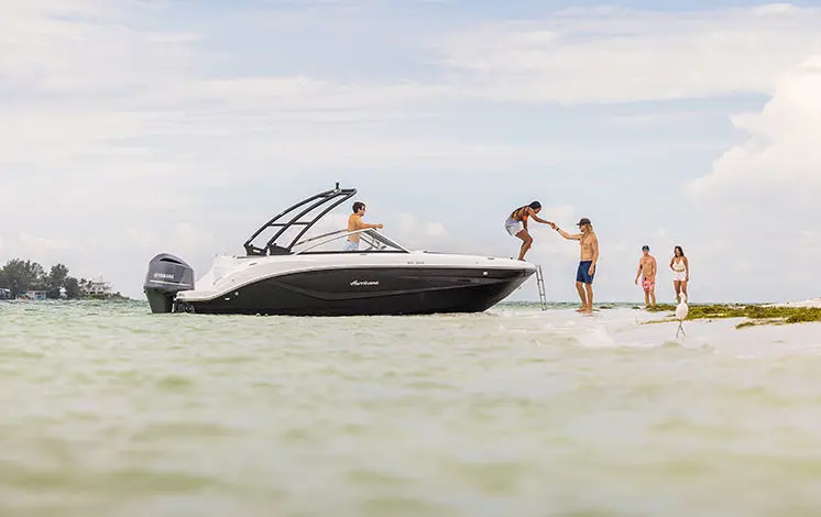 woman stepping off the bow of a hurricane boat onto a beach
