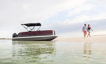 couple walking on a beach near their hurricane fundeck boat