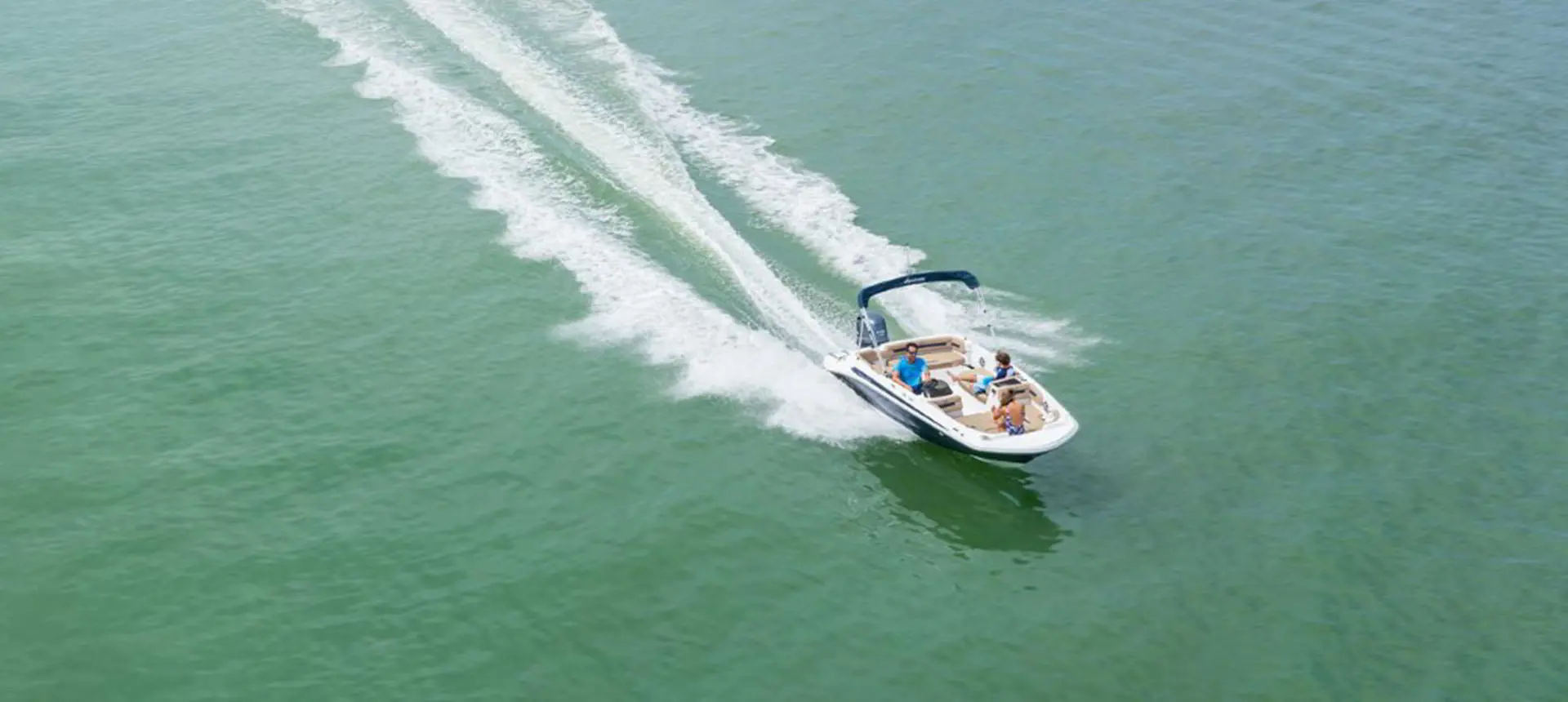 Aerial view of a Hurricane SunDeck Sport 185 OB deck boat on a lake.