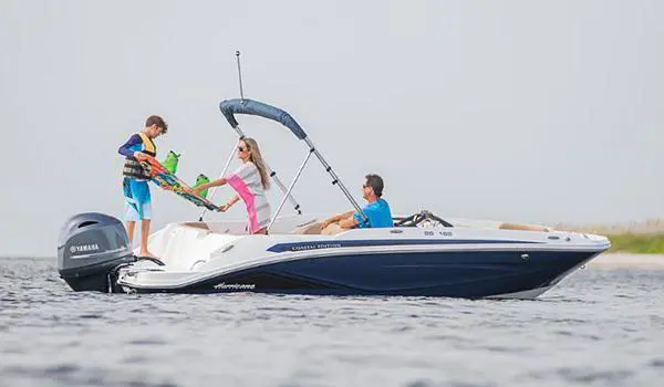 Kid preparing to wake board behind a Hurricane SunDeck Sport 185 OB deck boat.