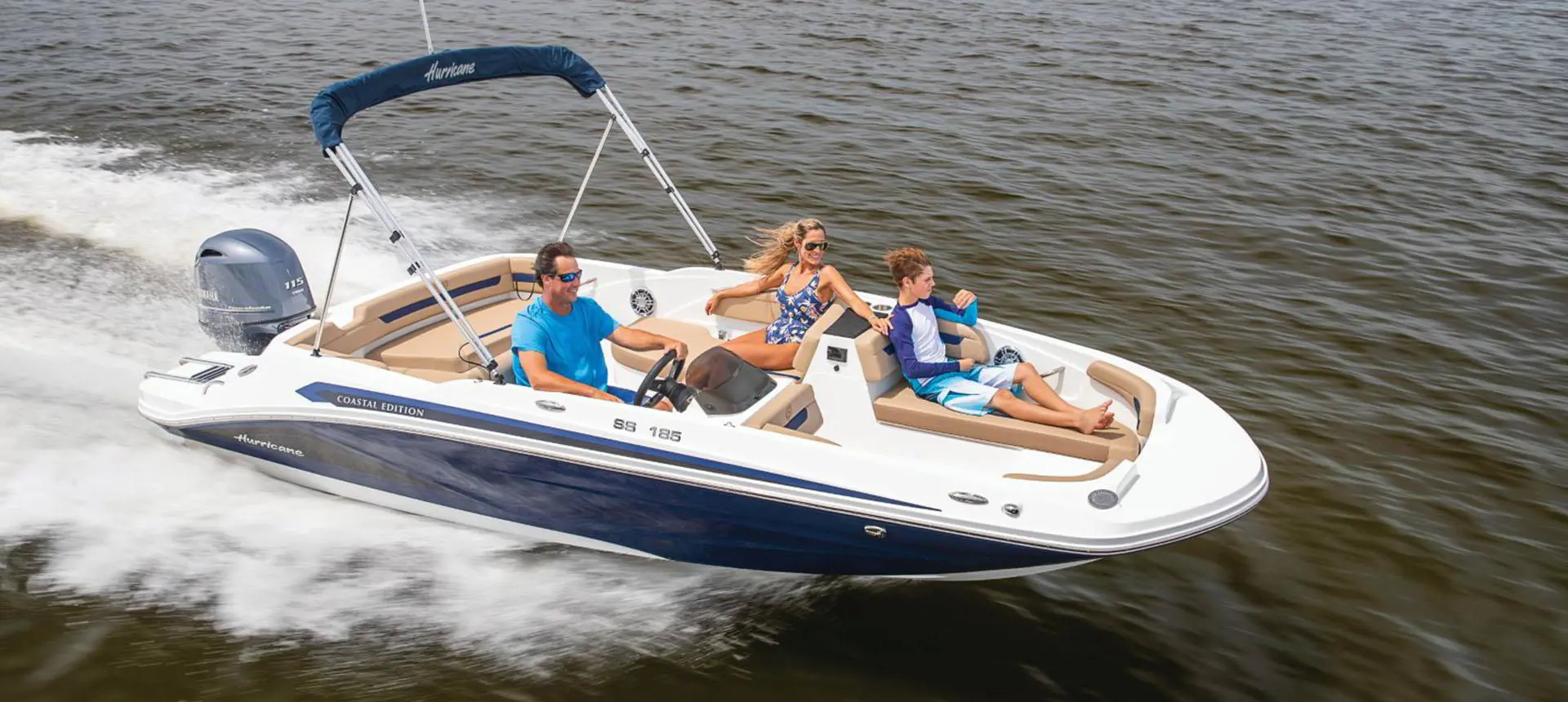 Hurricane SunDeck Sport 185 OB deck boat cruising across a lake.