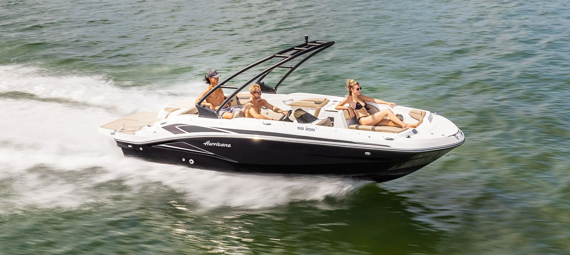 3 people cruising a lake on a Hurricane SunDeck Sport 205 IO deck boat.