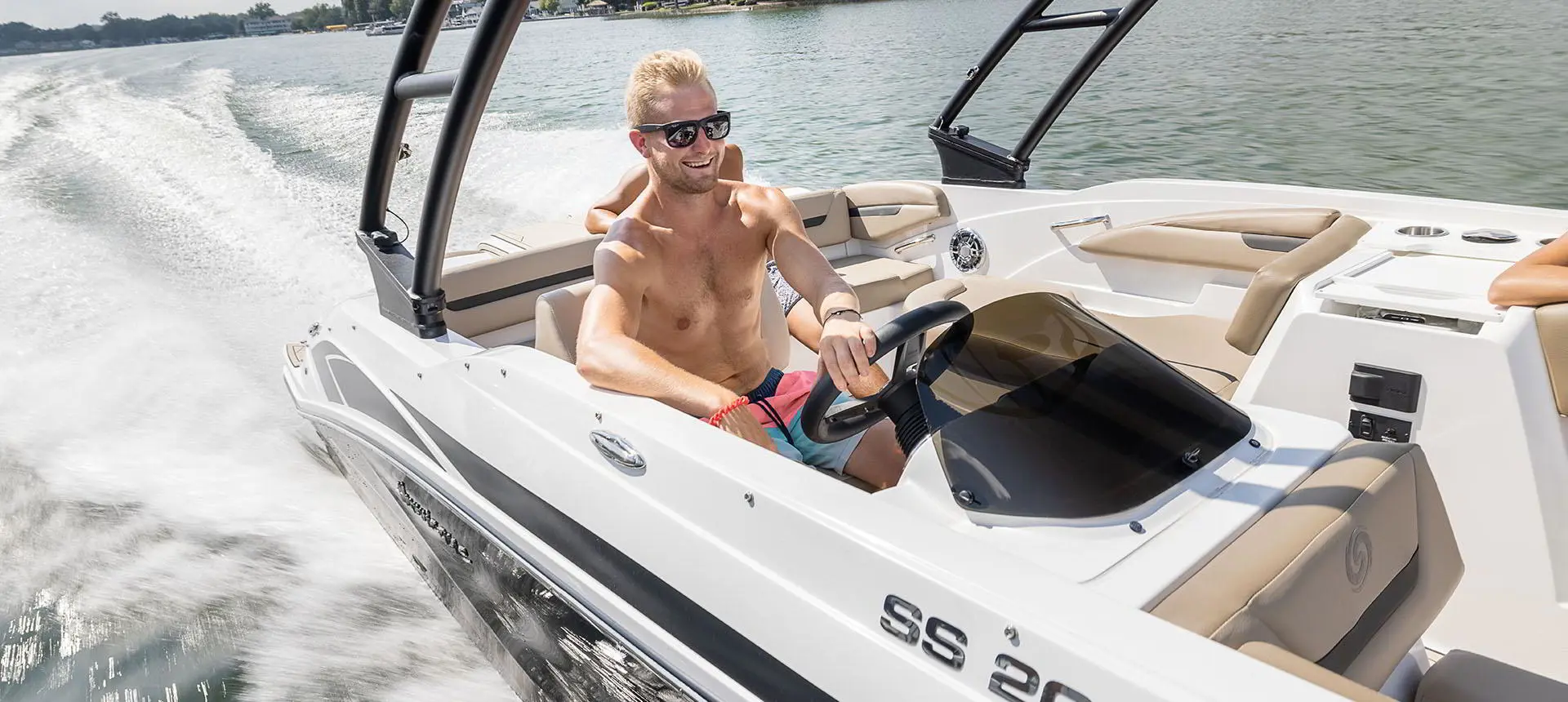 Man smiling while at the helm of a Hurricane SunDeck Sport 205 IO deck boat.