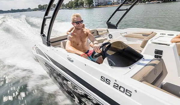 Man smiling while at the helm of a Hurricane SunDeck Sport 205 IO deck boat.