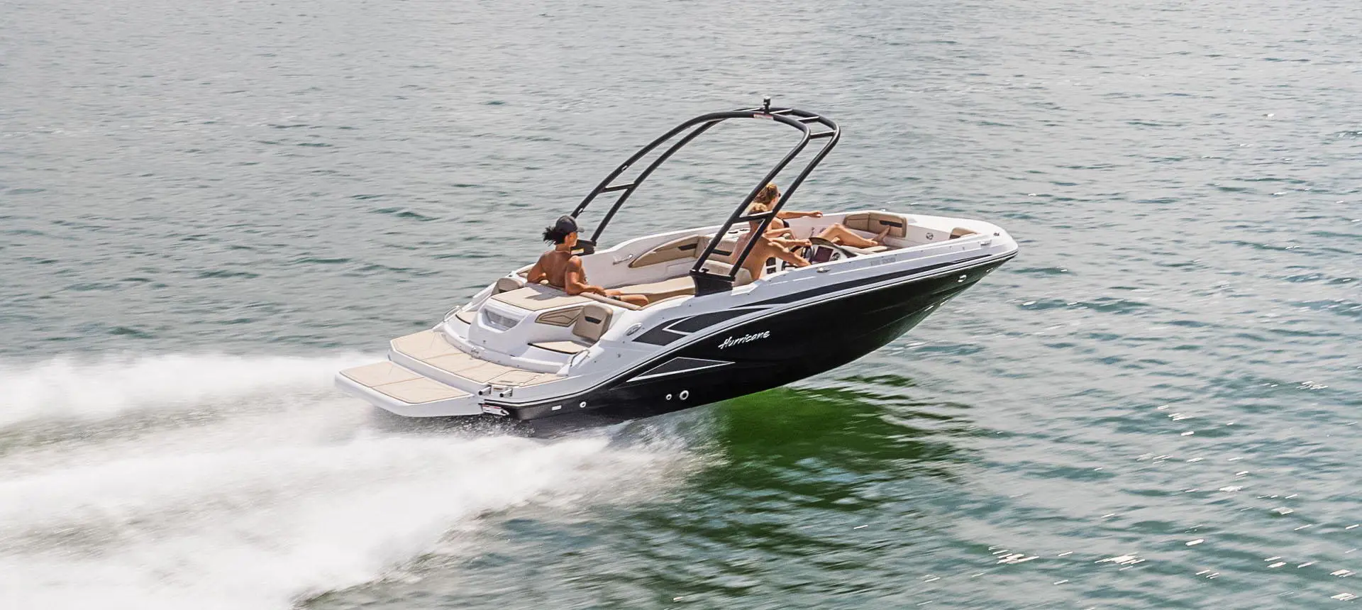 Stern focused view of a Hurricane SunDeck Sport 205 IO deck boat cruising on a lake.