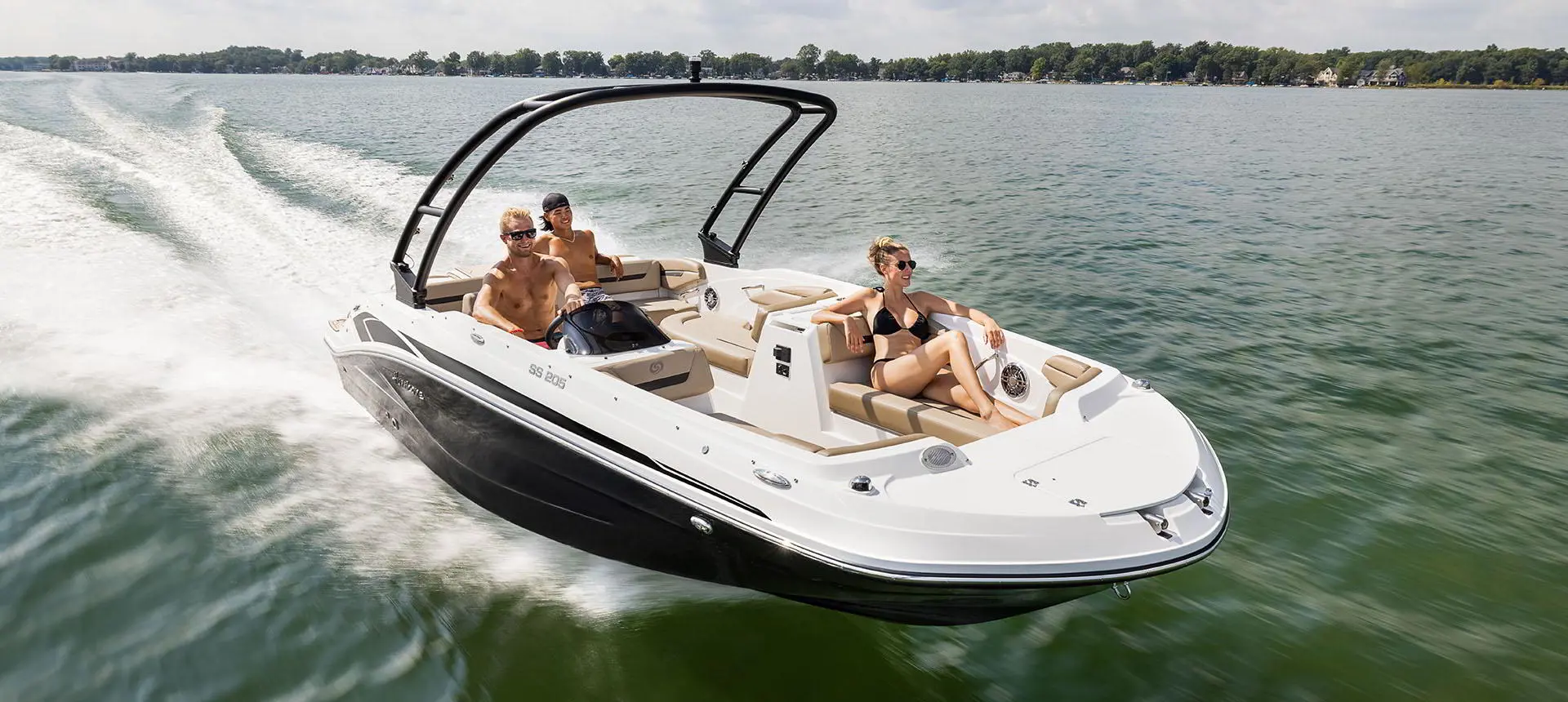 Bow focused view of 3 people cruising the lake on a Hurricane SunDeck Sport 205 IO deck boat.