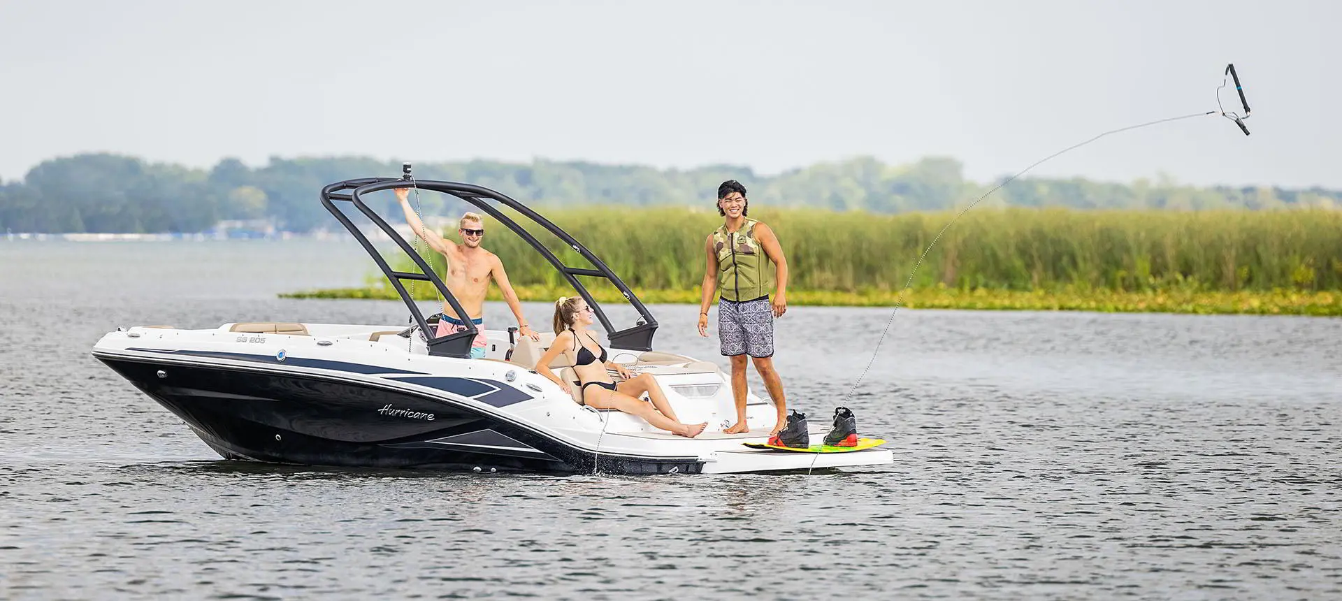 A person preparing to wakeboard behind a Hurricane SunDeck Sport 205 IO deck boat.