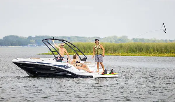 A person preparing to wakeboard behind a Hurricane SunDeck Sport 205 IO deck boat.