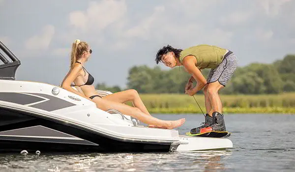 Man preparing to wakeboard behind a Hurricane SunDeck Sport 205 IO deck boat.