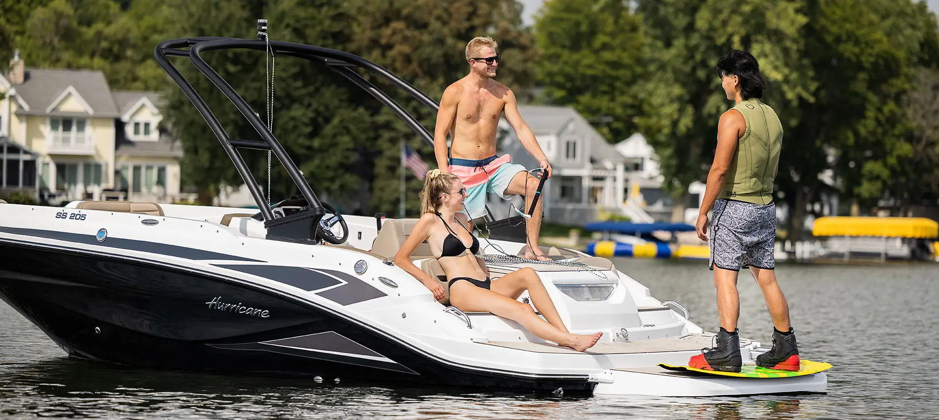 A man handing the tow rope to another man preparing to wakeboard behind a Hurricane SunDeck Sport 205 IO deck boat.