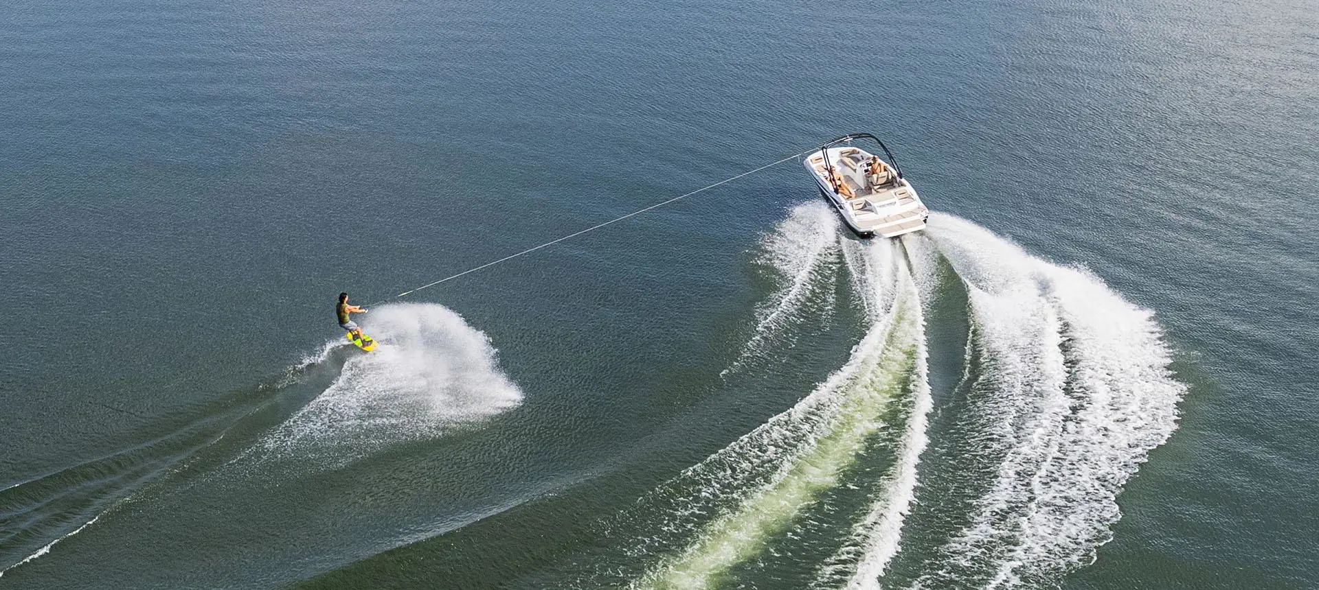 Wakeboarder being pulled behind a Hurricane SunDeck Sport 205 IO deck boat.