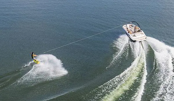 Wakeboarder being pulled behind a Hurricane SunDeck Sport 205 IO deck boat.