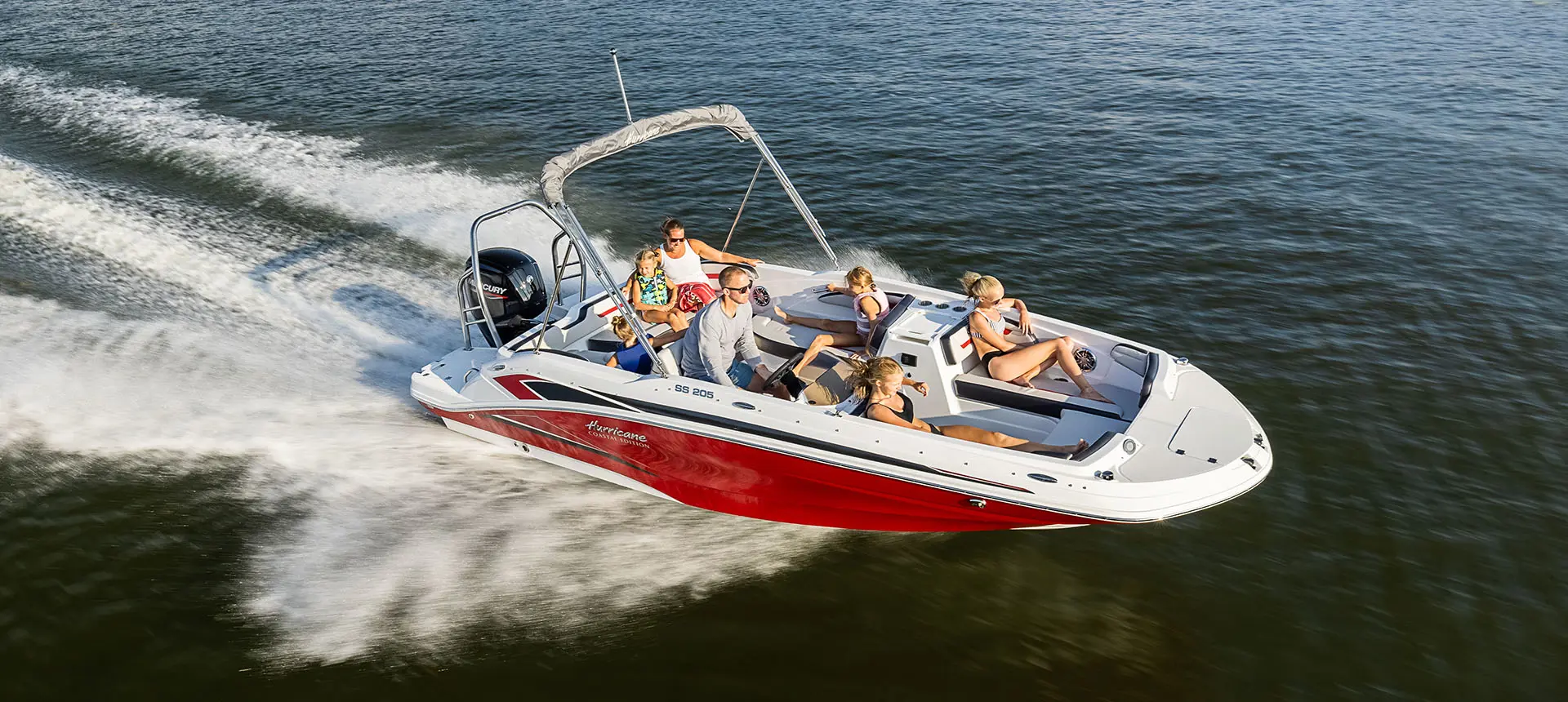 A family cruising the lake on their Hurricane SunDeck Sport 205 OB deck boat.