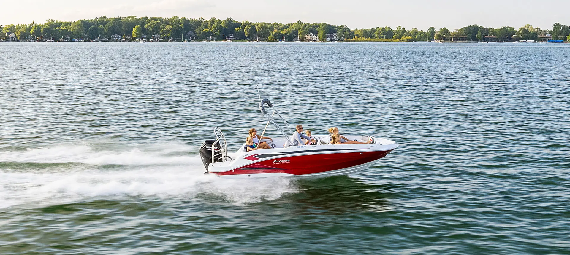 Side profile of a Hurricane SunDeck Sport 205 OB deck boat cruising on a lake.