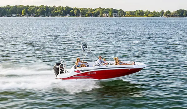 Side profile of a Hurricane SunDeck Sport 205 OB deck boat cruising on a lake.