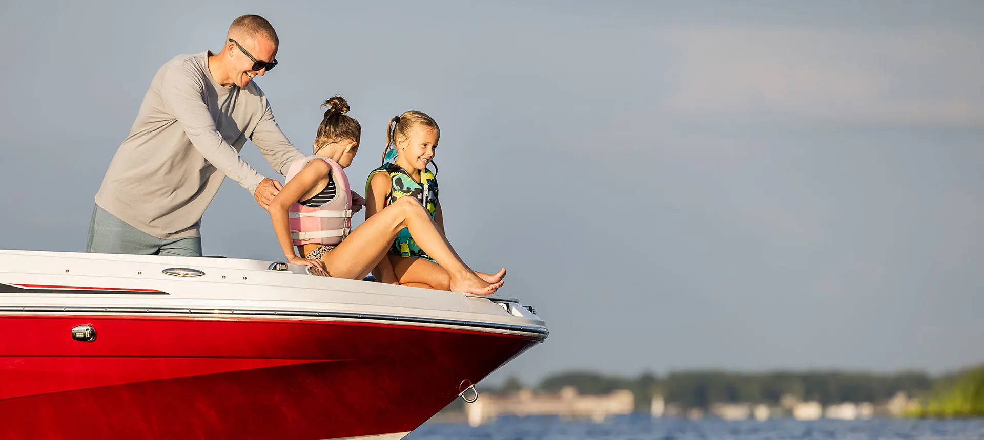 2 kids preparing to jump in the water with their life jackets off the bow of a Hurricane SunDeck Sport 205 OB deck boat.