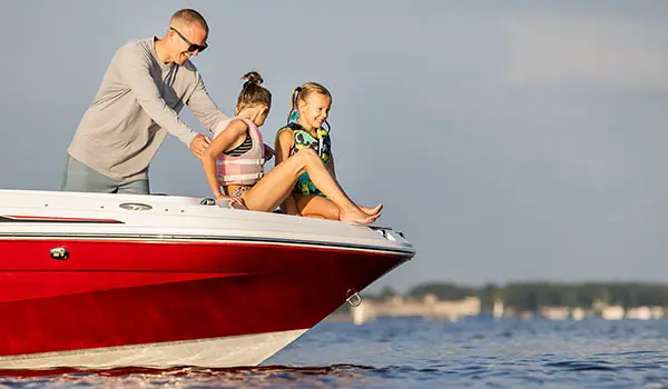 2 kids preparing to jump in the water with their life jackets off the bow of a Hurricane SunDeck Sport 205 OB deck boat.