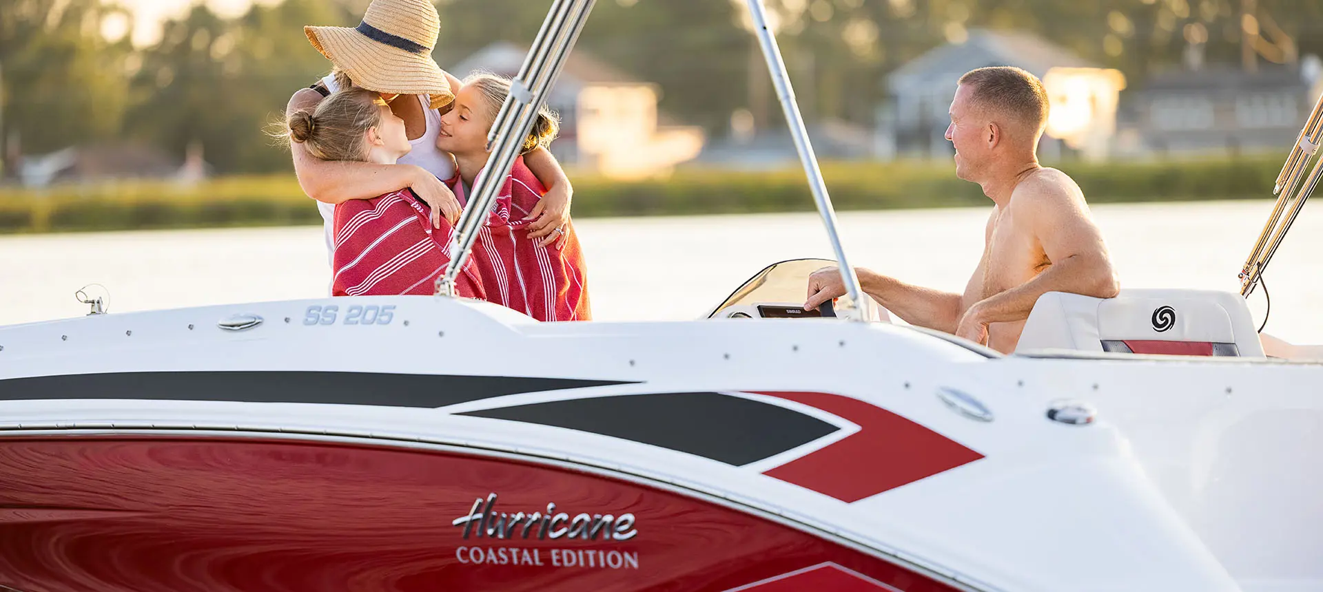 A mom wrapping her two daughters in a towel on a Hurricane SunDeck Sport 205 OB deck boat.