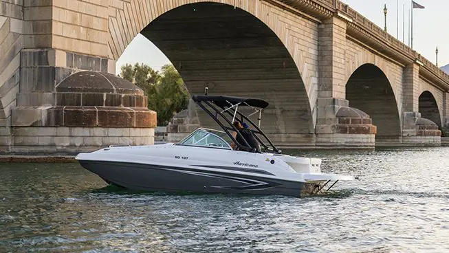 side profile of a hurricane sundeck io boat driving under a bridge