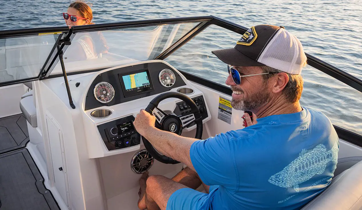 man smiling at the helm of a hurricane sundeck ob boat