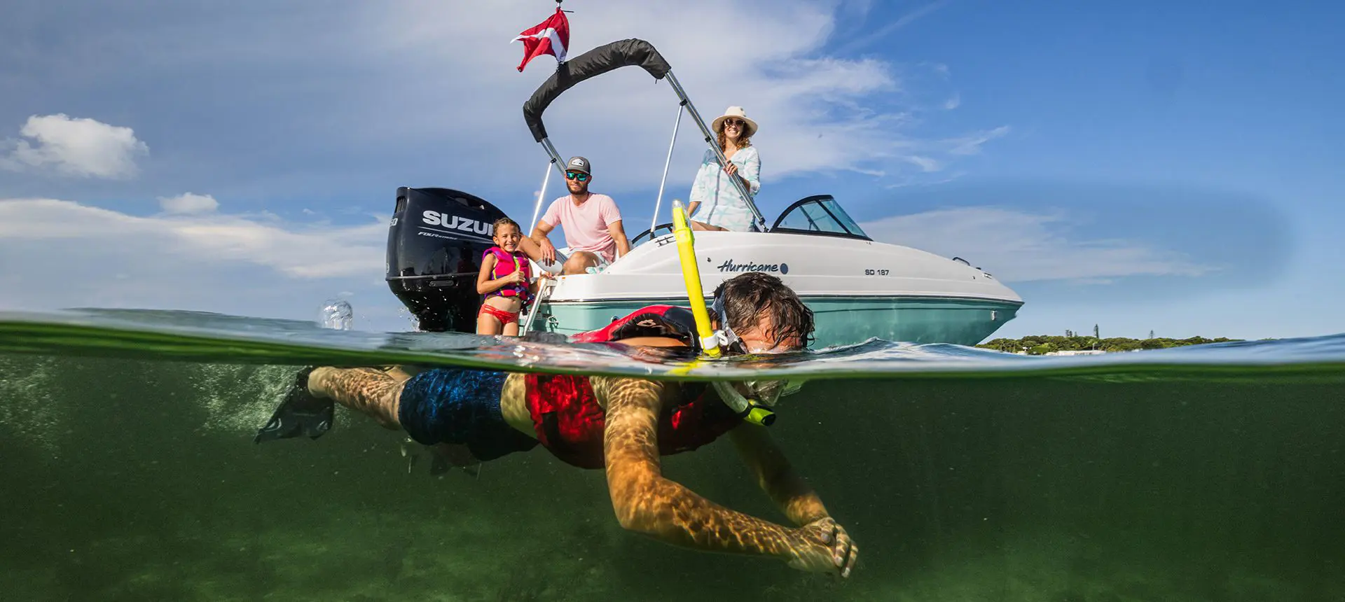 Kid snorkeling in the ocean while his family watches on a Hurricane deck boat.