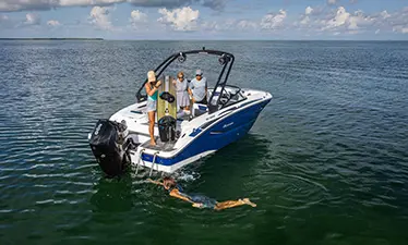 person swimming behind a hurricane sport boat preparing to wakeboard