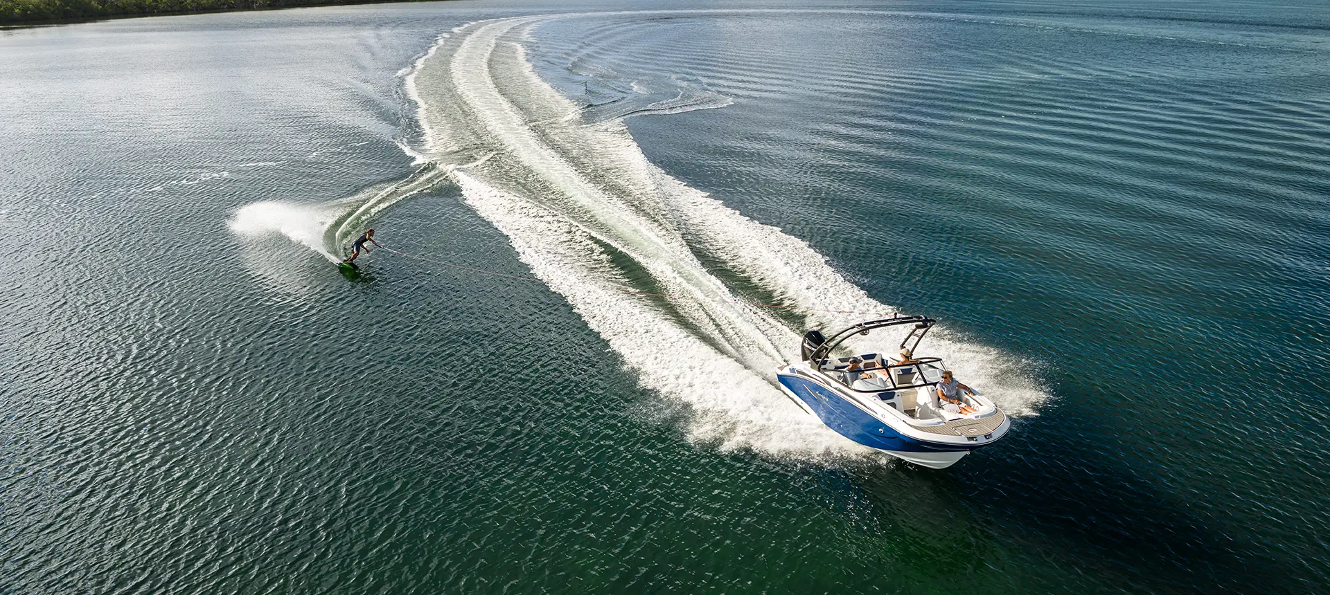 person wakeboarding behind a hurricane sport boat