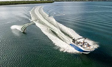 person wakeboarding behind a hurricane sport boat