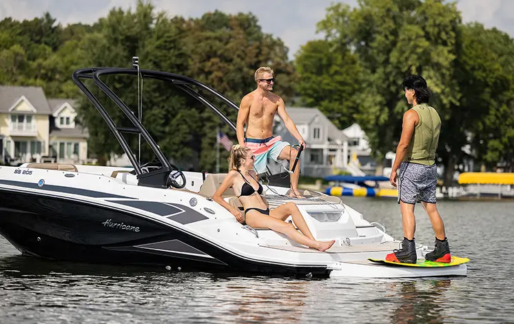 Man strapping in wakeboard on the back of a Hurricane sport boat.
