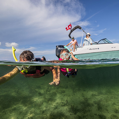 2 kids snorkeling near a Hurricane deck boat.
