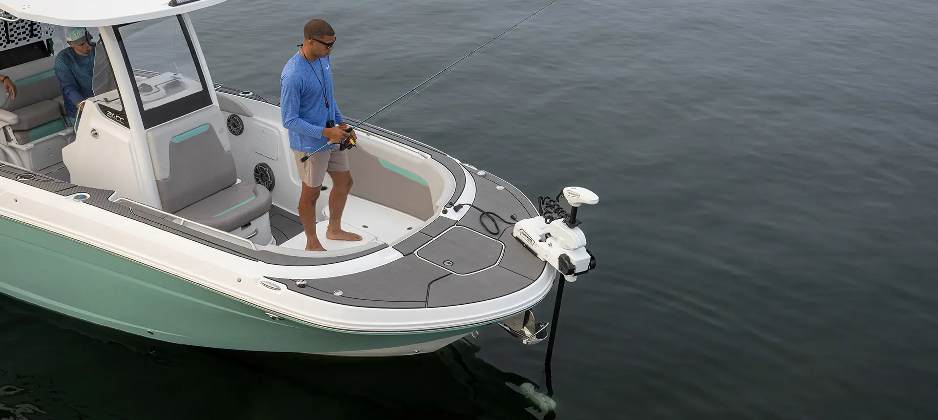 Man standing and fishing near the bow of a Hurricane Center Console fishing deck boat.