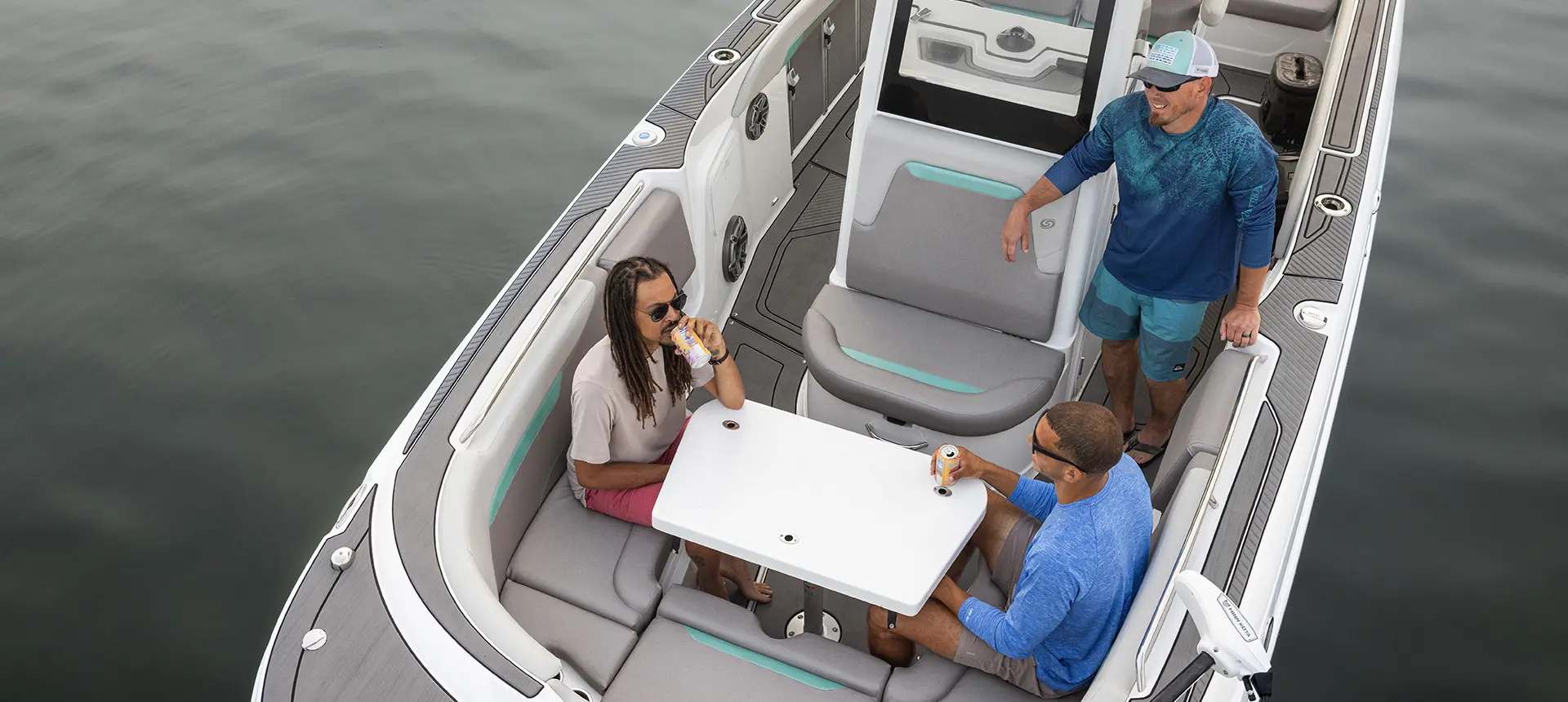 3 men chatting while drinking beverages on the bow of a Hurricane Center Console fishing deck boat.