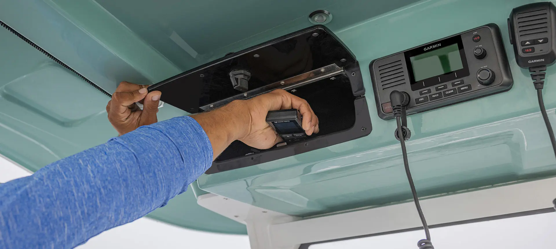 Man grabbing something from a storage area near the helm of a Hurricane Center Console fishing deck boat.