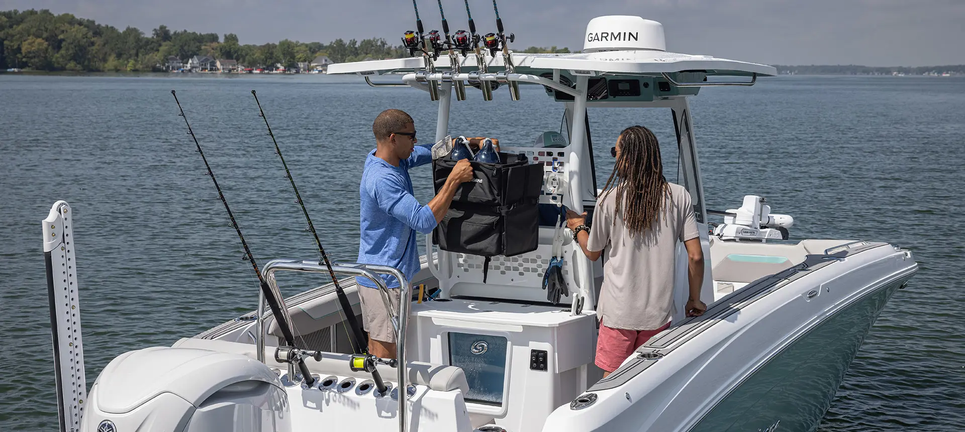 A man grabbing some gear from a storage bag on a Hurricane Center Console fishing deck boat.