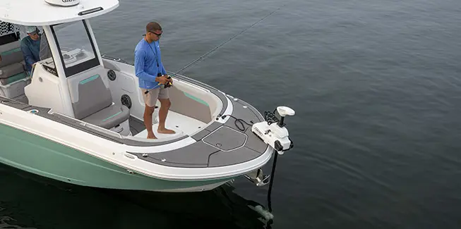 Man standing and fishing near the bow of a Hurricane Center Console fishing deck boat.