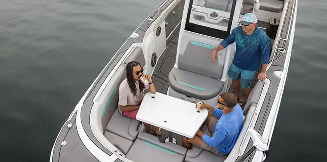 3 men chatting while drinking beverages on the bow of a Hurricane Center Console fishing deck boat.
