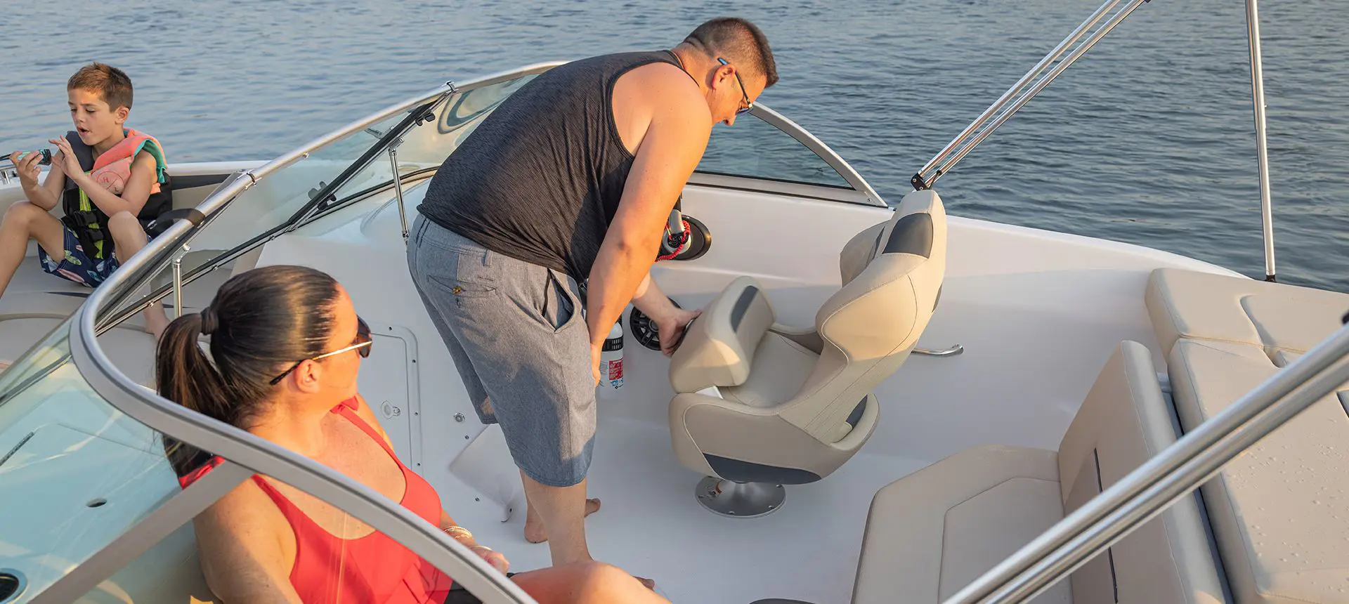 A man adjusting the captain's seat on a Hurricane 187 IO deck boat.