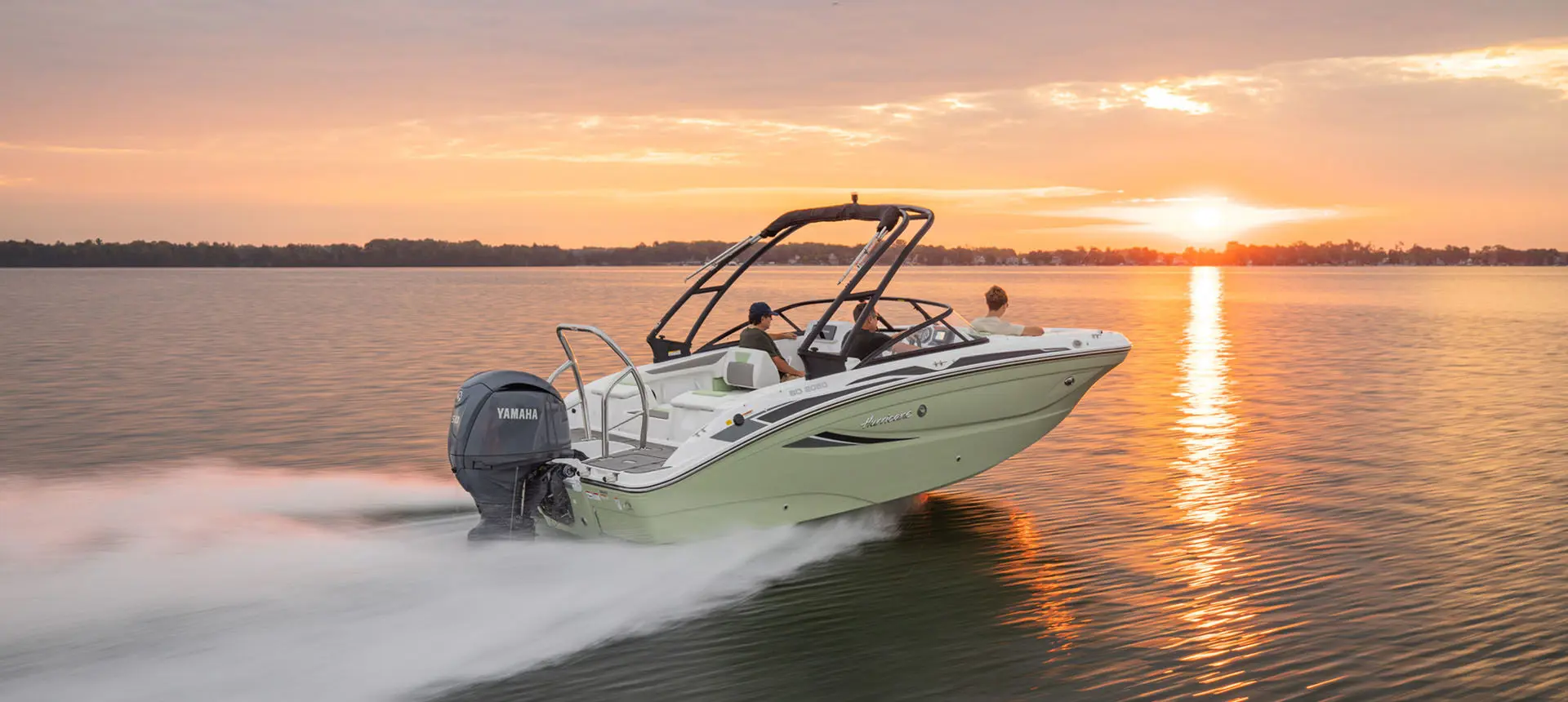 Rear-view of Hurricane Sundeck 2050 OB cruising on lake during sunset.