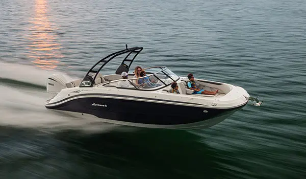 Hurricane Sundeck 2600 OB deck boat cruising on the ocean at sunset.