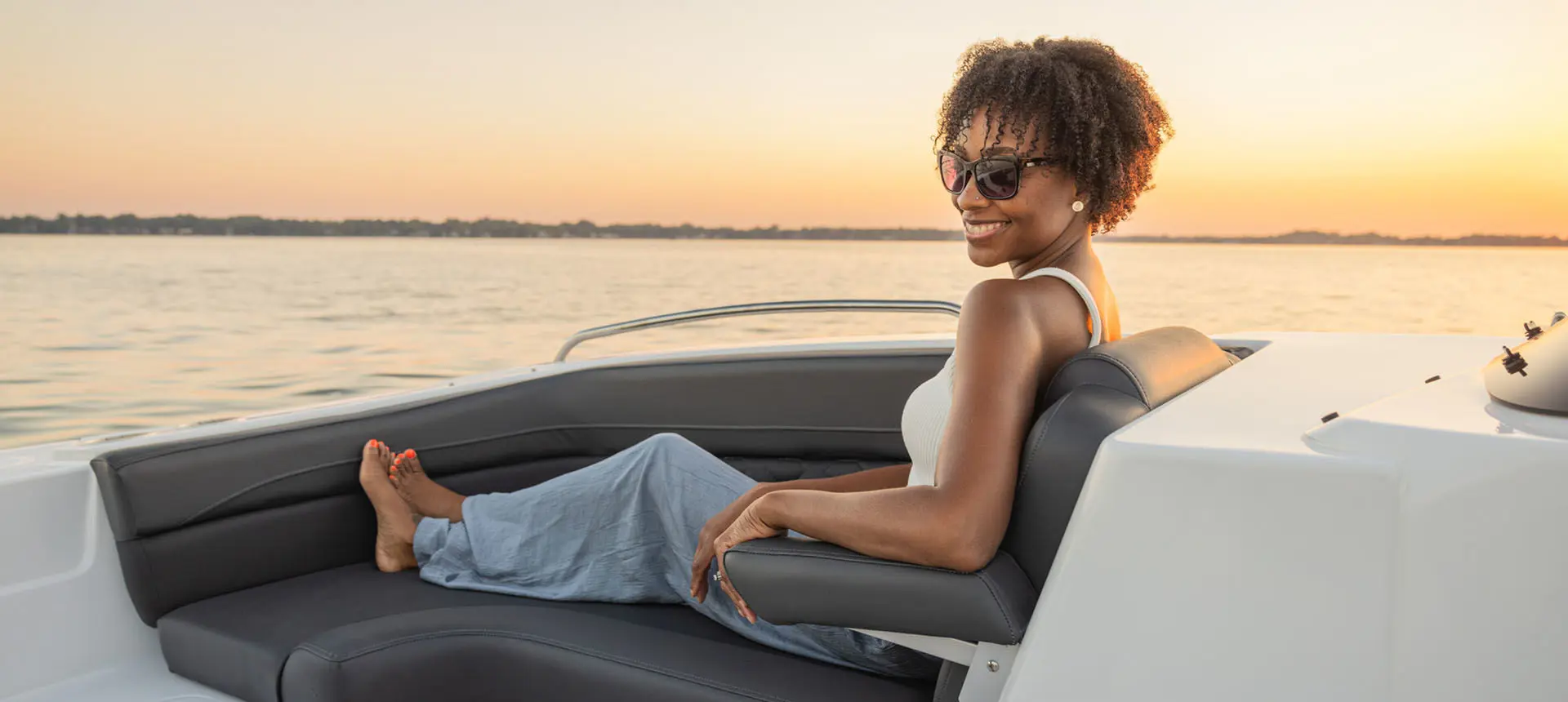 Woman lounges on front seating in a Hurricane Sundeck Sport 192 RL OB.
