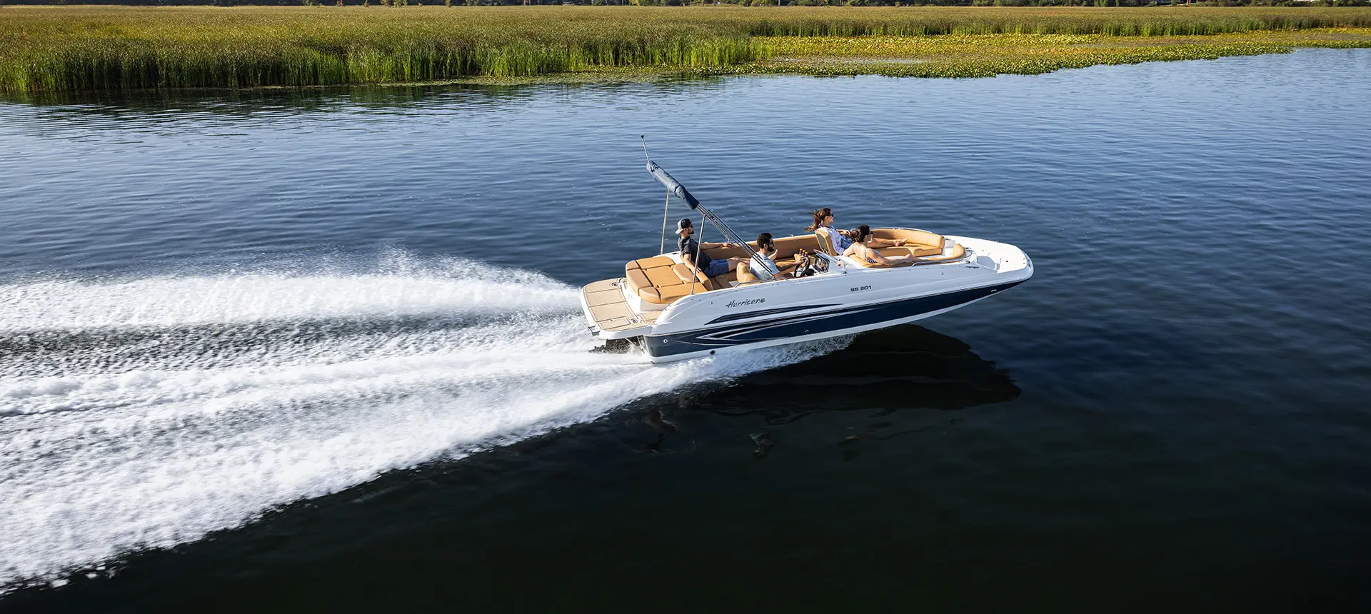 Side profile of a SunDeck Sport I/O 201 deck boat cruising across a lake.